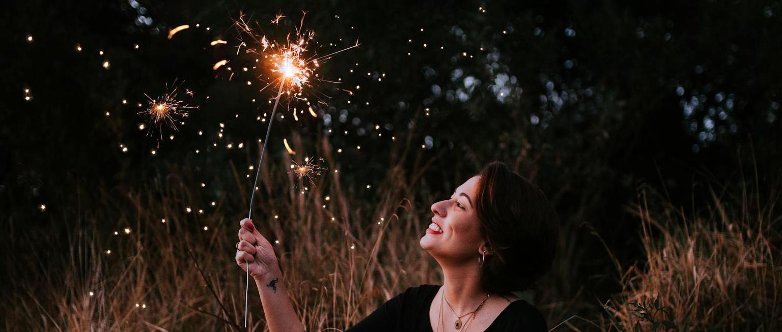 Woman holding sparkler under night sky