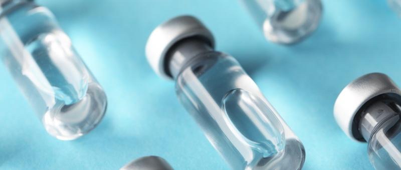 Vaccine in vials on light blue background.