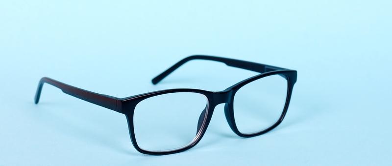 Unfolded black-framed glasses against a bright blue background.