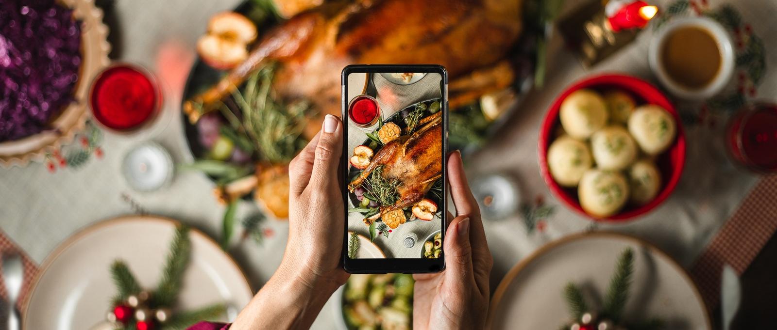 Woman using her smart phone to photograph a typical German Christmas dinner. Female taking pictures of Christmas menu on table.