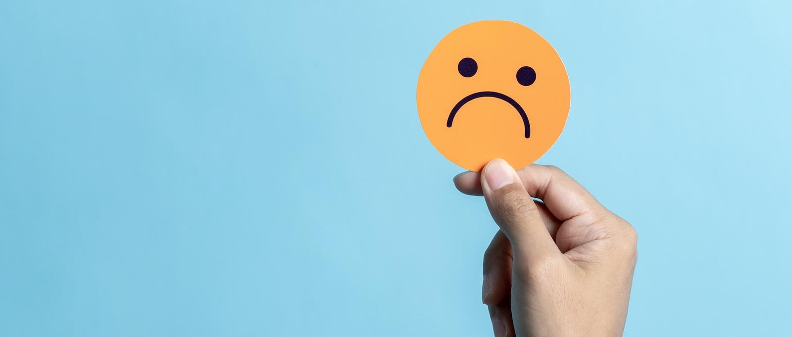 A orange circle with a sad face on it on a blue background.