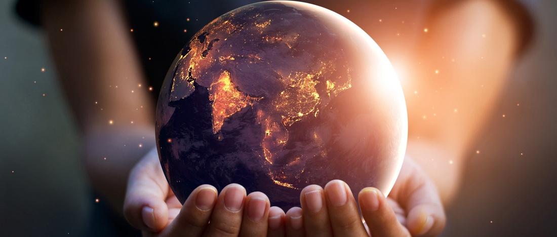 Earth at night held in human hands.