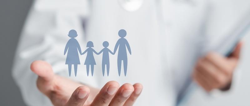 Hand holding a blue silhouette of a family with two adults and two children, representing family protection.