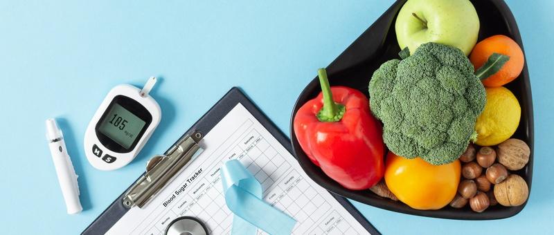 Fresh vegetables and fruit with blood sugar monitor top view on blue background.