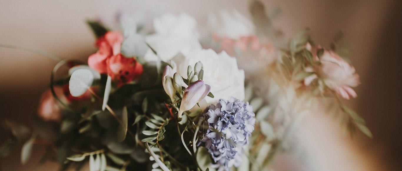 Elegant bouquet featuring white, coral, and lavender flowers with greenery in soft, dreamy focus.