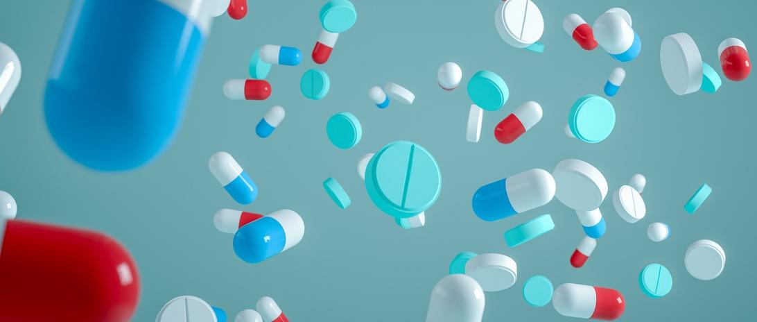 Falling antibiotic pills on blue background.